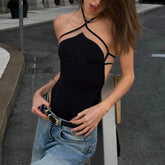 Woman wearing a black halter top and blue jeans on a city street.